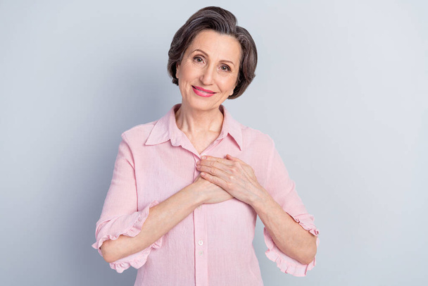 Photo of dreamy pretty mature lady wear pink clothes arms chest smiling isolated grey color background - Fotografie, Obrázek