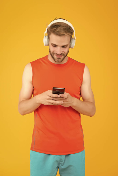 homem barbudo alegre ouvir música em fones de ouvido digitais usando aplicativo de telefone móvel vestindo roupas esportivas para treino, rede social - Foto, Imagem