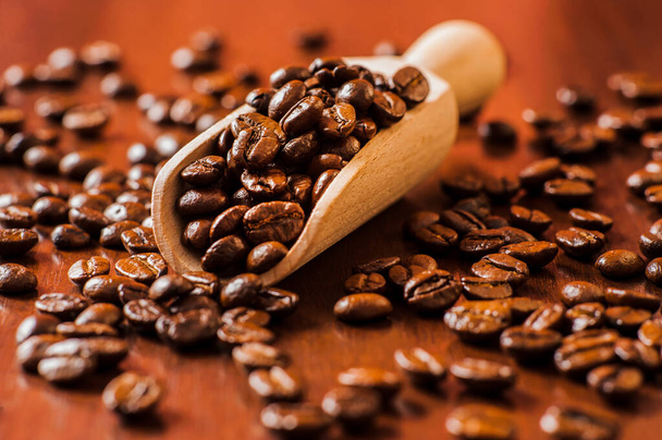 Closeup of coffee beans background.coffee beans on wooden table. Background of ground coffee texture. Coffee beans are scattered on the table. - Fotó, kép