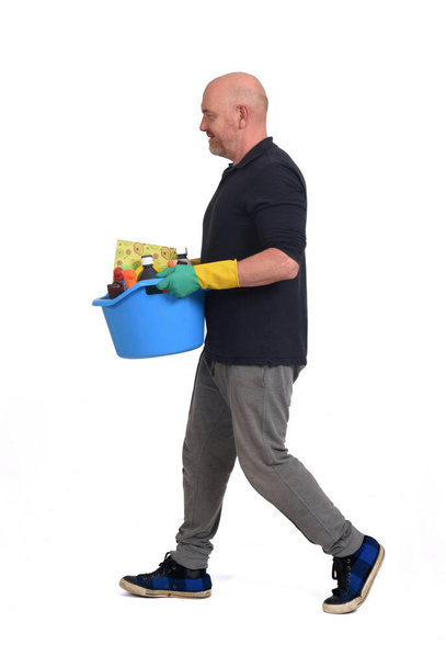 hombre caminando con un cubo y artículos de limpieza sobre fondo blanco - Foto, imagen
