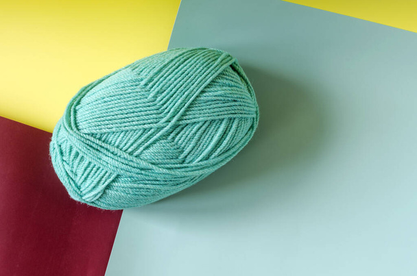 a ball of green yarn on a colored yellow-green-maroon background close-up knitting in self-isolation - Photo, image