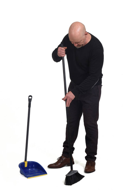 man with a broom and dustpan sweeping on white background - Photo, Image