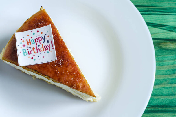 a piece of cake with the inscription happy birthday on a white plate close up - Fotó, kép