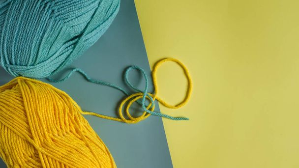 skeins of green and yellow yarn on a two-tone yellow-green background close-up view from above - 写真・画像