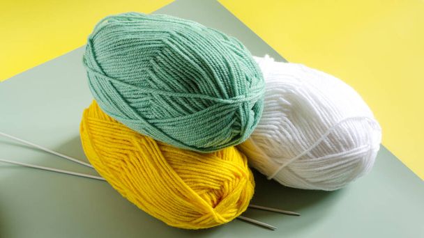 balls of green and yellow yarn on a colored yellow-green background close-up. Knitting concept - 写真・画像