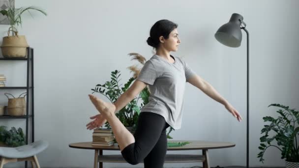 Young attractive multi ethnical woman wearing sportswear, pants and top, doing stretching yoga exercises on fitness in living room, healthcare and exercise mental therapy at home concept - Footage, Video