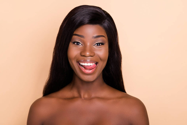 Photo of happy charming dark skin nude woman smiling licking lips isolated beige color background - Fotografie, Obrázek
