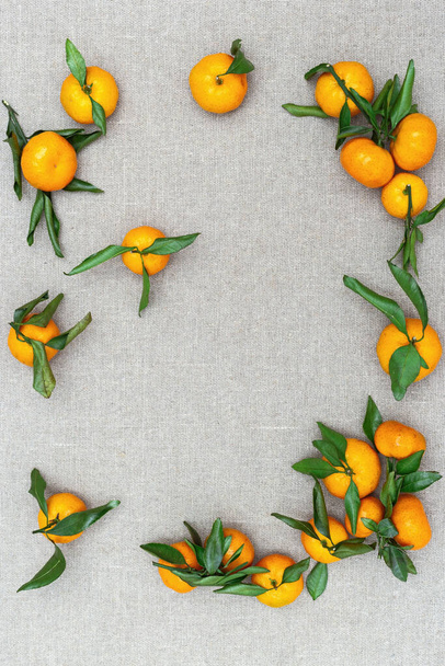 素朴な背景に葉を持つマンダリンオレンジ。コピースペースの柑橘類。上からの眺め. - 写真・画像
