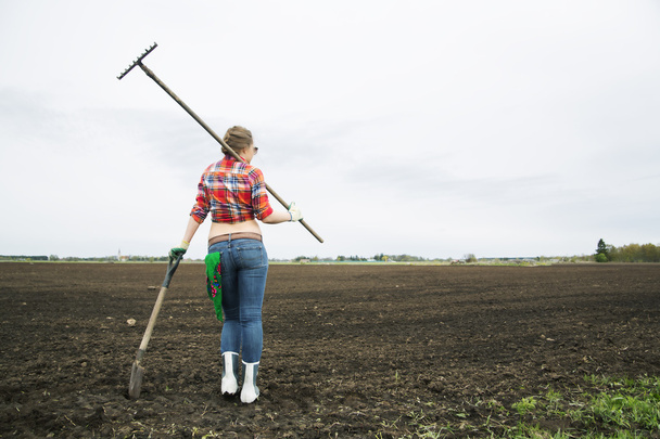 Woman with rake and shovel move away - Фото, изображение