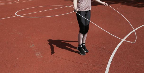 Mujer joven saltando la cuerda de salto en un campo deportivo - Foto, imagen