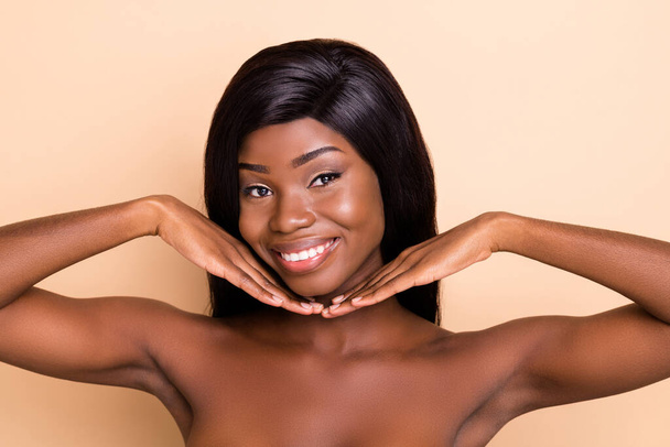 Photo of dreamy happy dark skin nude woman hands arms cheeks cheekbones isolated beige color background - Foto, Imagem