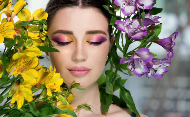 Fashion model with creative professional make-up with purple and yellow color and flower. SPA and wellness, bodycare and skincare concept. - Foto, immagini