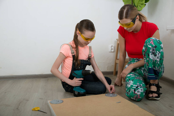 Two girls with tools mending furniture on the floor in the room. Little girl and young woman are doing homework. Professions and career. Female choice. - Fotografie, Obrázek