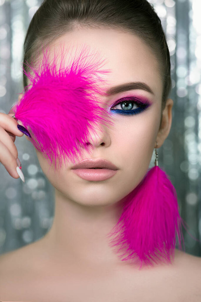 Portrait of beauty model with bright color makeup. Face of beautiful young woman with professional make up  and vivd pink feathers. Close up, selective focus. - Fotó, kép