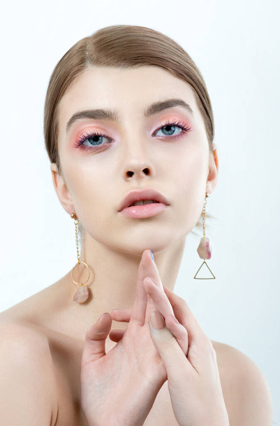Beautiful young woman with clean perfect skin and blue-pink makeup and feather earings. Portrait of beauty model with natural make up and long eyelashes. Youth and skin care concept. Spa, skincare and wellness. - Foto, Imagem