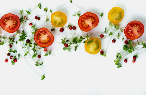 Close up composition of cutted red and yellow cherry tomatoes with microgreens and pink pepper on light background. - Foto, imagen