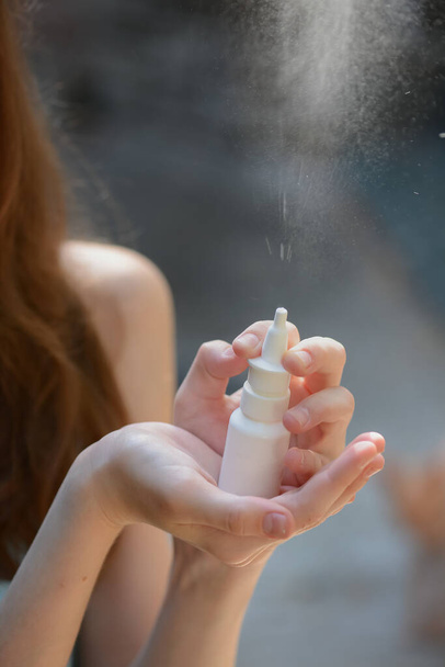 Retrato de niña hermosa con botella blanca limpia de aerosol nasal de protección. Un niño rociando medicinas. Higiene y salud. Prevención de infecciones. Enfoque selectivo. - Foto, imagen