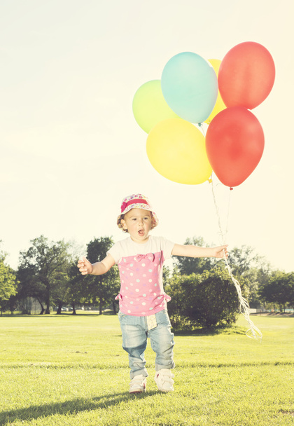 Child with balloons on the field - Φωτογραφία, εικόνα