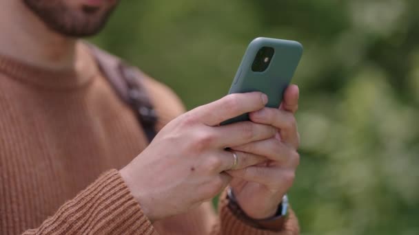 Κοντινό πλάνο ενός κινητού τηλεφώνου στα χέρια ενός άνδρα ταξιδιώτη που περπατάει μέσα στο δάσος. Κοινωνικά δίκτυα Πλοηγός και αγγελιοφόρος. Χρησιμοποιήστε το κινητό σας τηλέφωνο για μια βόλτα στο δάσος - Πλάνα, βίντεο