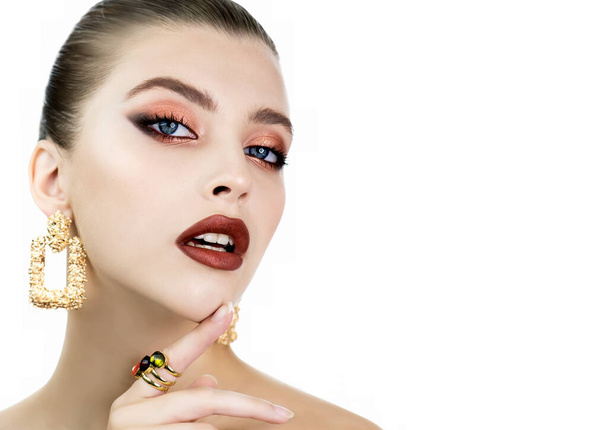 Beautiful young woman with luxury makeup and jewelry. Portrait of beauty fashion model with professional golden color make up and long eyelashes. - Valokuva, kuva