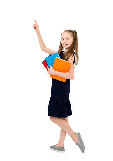 Happy cute smiling cheerful child girl in school uniform holding books. Schoolgirl with facial expression isolated on white. Concept of education, reading, back to school. - 写真・画像