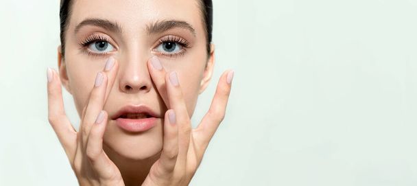 Beautiful young woman with clean perfect skin. Portrait of beauty model with natural nude make up and and hand with manicure touching face. Spa, skincare and wellness. Close up, background, copyspace. - Φωτογραφία, εικόνα