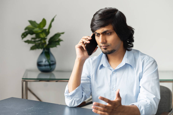 Upset indian businessman is talking on the smartphone - Foto, Bild
