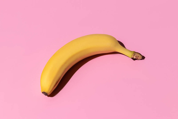 ripe yellow bananas isolated on a pink background. hard shadows from the sun at noon. travel and entertainment concept with copy space - Fotó, kép