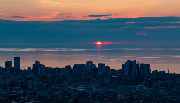 Μια εικόνα του ήλιου που δύει πάνω από τη Μαύρη Θάλασσα και την πόλη της Batumi. - Φωτογραφία, εικόνα