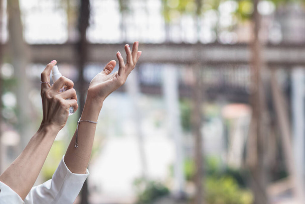 Una giovane donna d'affari usa uno spray alcolico sul palmo della mano per purificare e prevenire la diffusione del virus coronavirus 2019 (COVID-19). Spray alcolico può uccidere Corona Virus 2019 (COVID-19). - Foto, immagini