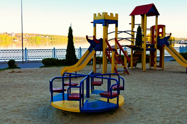 Kilátás üres színes modern gyermekek játszótér a Taras Shevchenko Park. Városi tó a háttérben. Szcenírozott tavaszi reggel. Ternopil, Ukrajna. - Fotó, kép