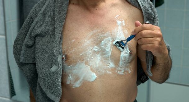 Borst van een man die waxen met een scheermes - Foto, afbeelding