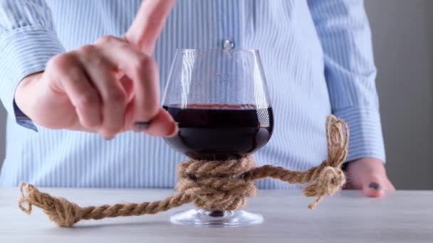 mano femminile mostra il segno non può, fermare su un bicchiere di vino, legato con una corda di iuta. Il concetto di dipendenza da alcol. Il problema del trattamento dell'alcolismo - Filmati, video