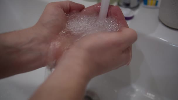 Mani di un uomo sotto un rubinetto con acqua corrente limpida - Filmati, video