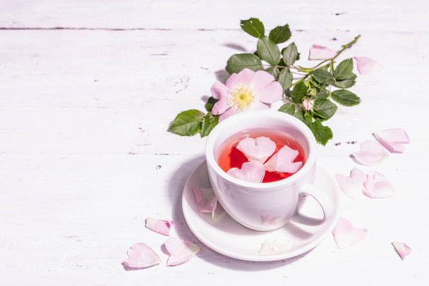 Gül kalça çiçekleri çayı. Yaz vitamini içeceği, sert ışık, karanlık gölge. Beyaz tahta arkaplan, boşluğu kopyala - Fotoğraf, Görsel