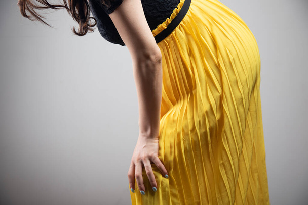 a young woman in a dress has a knee pain - Foto, afbeelding