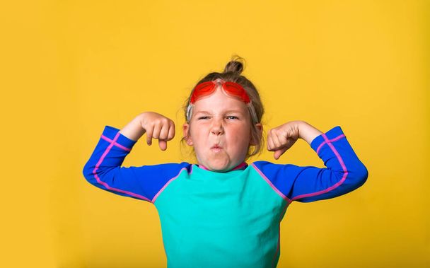 Back to sport school. Strong proud little child shows muscles. Funny nerd kid make emotional grimace. Geek sportish child isolated on yellow. Education and creativity concept - Photo, Image