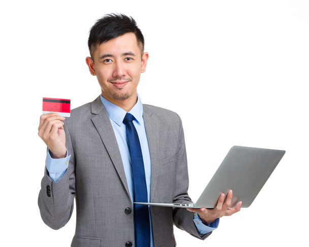 Бізнесмен тримає кредитну картку і ноутбук
 - Фото, зображення