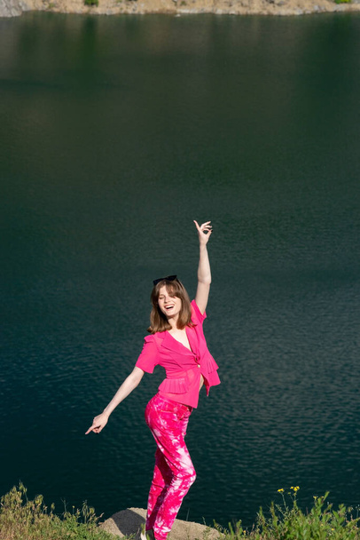 ピンクでファッショナブルな若い女の子の肖像画、世代z 。湖の水の背景に. - 写真・画像