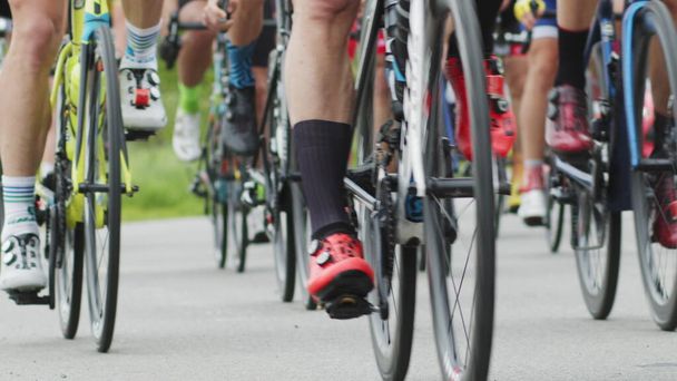 Shallow focus shot of cyclists lower bodies while riding bikes in cycling race. The bicycle wheel is spinning. Bicycle wheel rotation. Cyclist training. Sports Healthy lifestyle. - Photo, Image