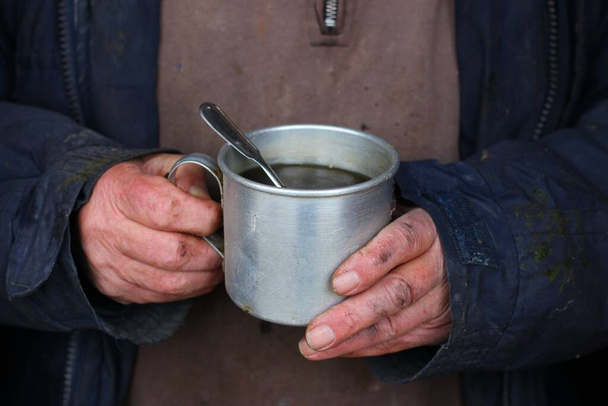 Бідний чоловік тримає чай, щоб зігрітися взимку
. - Фото, зображення