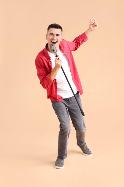 Handsome young man with microphone on color background - Фото, зображення