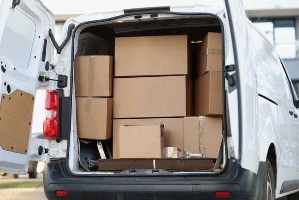 Un montón de cajas de cartón están en minivan con puerta abierta de cerca - Foto, Imagen