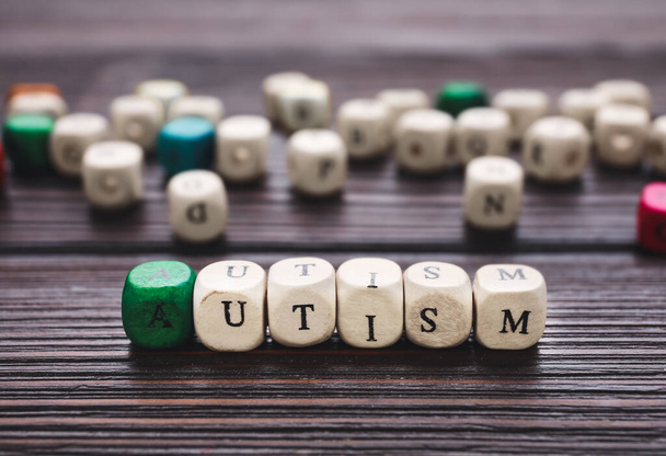 Word AUTISM made of cubes on dark wooden background, closeup - Foto, Bild