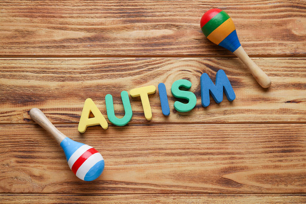 Word AUTISM and maracas on wooden background - Photo, Image