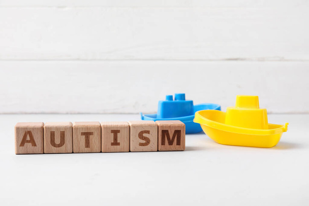 Word AUTISM and toys on white wooden background - Foto, Imagen