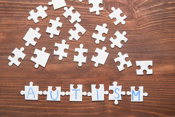 Word AUTISM made of puzzles on dark wooden background - 写真・画像