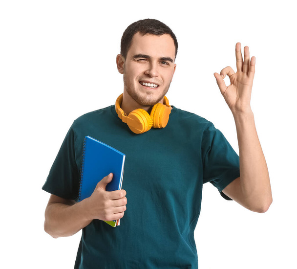 Young man with headphones showing OK on white background - Photo, image
