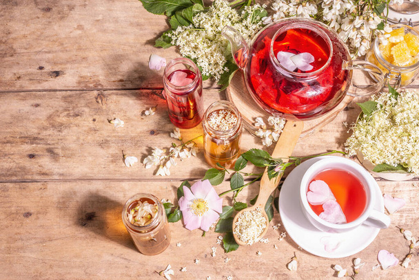 花から作られた盛り合わせ茶。新鮮な高齢者のベリー、バラのヒップ、およびアカシア。健康食品の概念。古い木の板の背景、トップビュー - 写真・画像