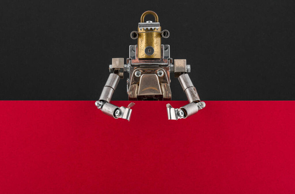 Portrait of a steampunk robot looking around the corner of red and black empty board with space for copy - Foto, imagen